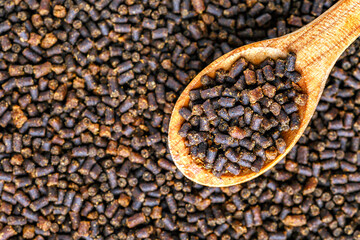 Dry food for aquarium fish on a wooden spoon compound fish feed flakes.Pile of flakes and granules for feeding tropical aquarium fishTop view.Aquarium