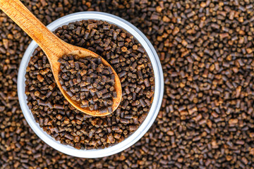 Dry food for aquarium fish on a wooden spoon compound fish feed flakes.Pile of flakes and granules for feeding tropical aquarium fishTop view.Aquarium