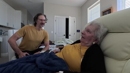 An elderly woman shares a heartfelt conversation with her son while enjoying time together at the nursing home.