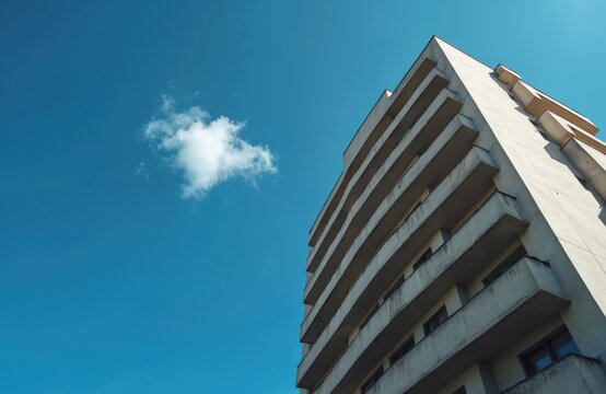 Skyscraper against blue sky. Building with repetitive balcony lines. Cloud floats. Facade of residential multistory building against clear sky. Concept of urbanization with modern apartment blocks. - Powered by Adobe