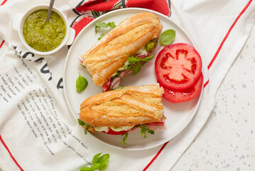 Baguette sandwich with pesto, prosciutto, tomato, burrata and arugula.selective focus