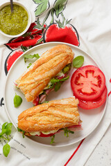 Baguette sandwich with pesto, prosciutto, tomato, burrata and arugula.selective focus