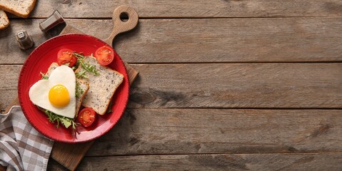 Plate with tasty heart-shaped fried egg, toasts, tomatoes and arugula on wooden background with...
