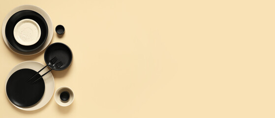 Stylish ceramic plates, bowls and forks on beige background