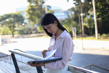 Female professional reviewing documents outdoors in a semi-urban office.