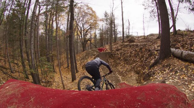 Extreme sports athlete riding an enduro downhill mountain bike on a black diamond flow trail full of jumps