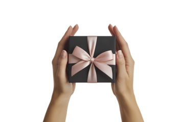 Pair of hands carefully presenting elegant black gift box tied with soft pink satin ribbon, symbolizing thoughtful present