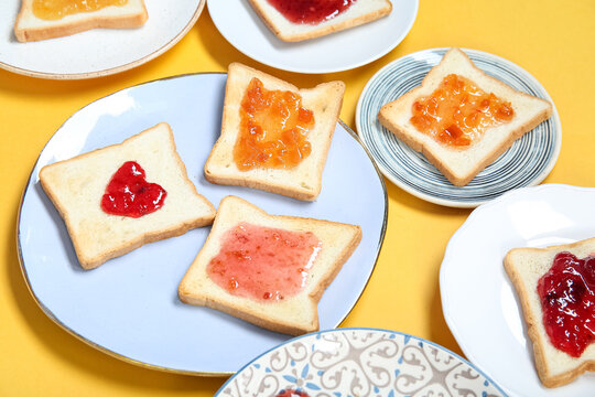 Many plates of delicious toasts with jam on color background, closeup
