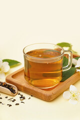 Cup of aromatic tea, dried leaves and beautiful jasmine flowers on color background, closeup