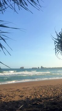 The sea in Jember, East Java. Indonesia. Watu Ulo beach with dark sand, mountains and coral rocks towering above the beach. The raging blue Indian ocean on a sunny day. 4К