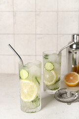 Glasses of mojito with cucumber on grunge white table