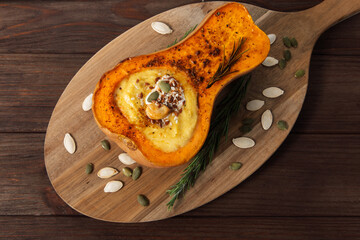 Delicious baked pumpkin filled with creamy soup, sprinkled with seeds and herbs
