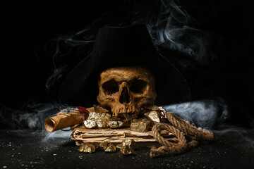 Travel equipment with golden nuggets, human skull, old manuscripts and pirate hat on black background © Pixel-Shot