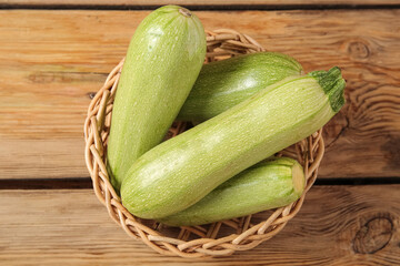Wicker bowl with fresh green zucchini on wooden background