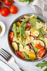 Bowl of tasty pasta salad with pepper and tomatoes on white background