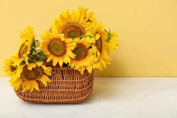 Wicker basket with beautiful sunflowers on white table