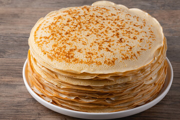 Thin pancakes on a wood table. Homemade crepes, tasty food. Staple of yeast pancakes, traditional for Russian pancake week (Shrove tide). Thin pancake with crispy crust