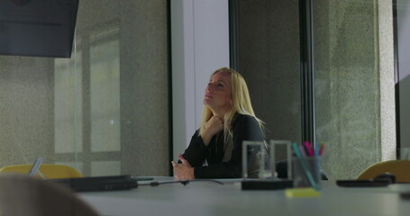 Pensive businesswoman sits alone in empty office, gazing into distance with worried expression, silently contemplating future decisions and professional uncertainty