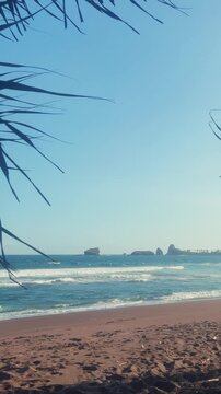 The sea in Jember, East Java. Indonesia. Watu Ulo beach with dark sand, mountains and coral rocks towering above the beach. The raging blue Indian ocean on a sunny day. 4К	