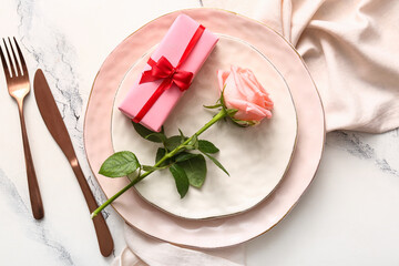 Beautiful table setting with rose and gift for Valentine's Day on white grunge background