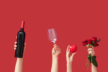 Female hands with heart, red roses, glass and bottle of wine on color background. Valentine's Day celebration