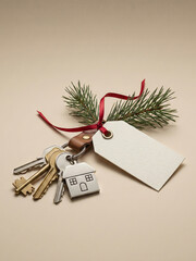 A festive keychain with house keys, a blank tag, and a pine sprig tied with a red ribbon rests on a neutral background