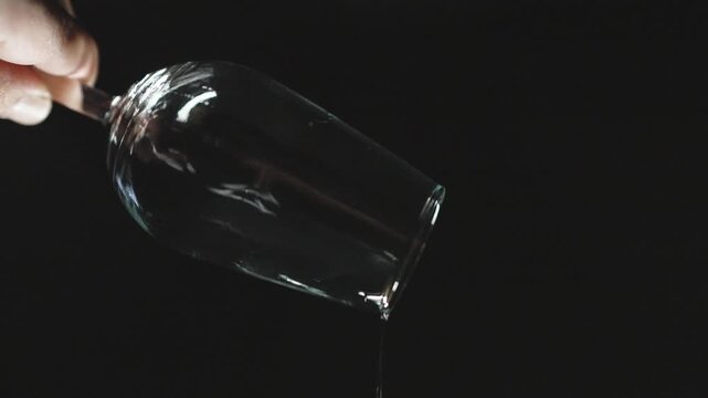 emptying a glass of sherry on a black background