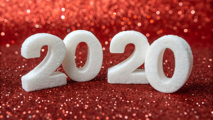 Close-up of a white foam numeric figure 20 set against a shimmering red glitter backdrop, evoking themes of celebration and significant milestones.