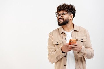 Smiling man holding a smartphone, looking away, enjoying social media or communication