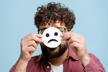 Man hiding actual emotions behind a sad face emoji, dealing with mental health