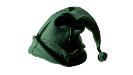A close up view of a green elf hat with a pom pom on the end against a black background in studio lighting