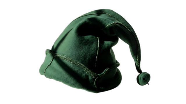 A close up view of a green elf hat with a pom pom on the end against a black background in studio lighting