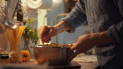 A person stirs a bowl of fresh vegetables with a wooden spoon, surrounded by kitchen tools and ingredients. This scene captures the warmth of home cooking in a cozy kitchen setting