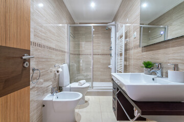 A stylish bathroom featuring a glass shower, modern sink, and sleek tiles. Soft lighting creates a calming atmosphere in this well-designed space