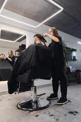 Professional woman barber wielding electric hair clipper making Fashionable haircut. Bearded Man client visit gentleman grooming beauty salon for hairstyle care. Modern Haircut style in barber shop