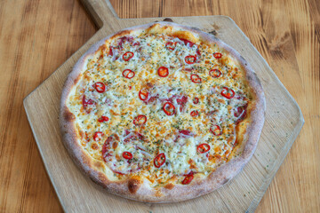 Delicious pizza topped with chili peppers and cheese on a wooden board, showcasing vibrant colors and appetizing textures for food lovers