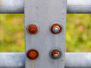 Rusty and clean metal bolts on a fence structure as a technical industrial texture for design