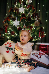 Little girl sitting near Christmas tree at the holiday