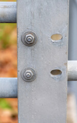 Two metal bolts on a galvanized support with oval holes as an industrial technical texture