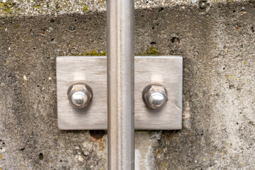 Polished metal bolts on the handrail attachment to the concrete base as a clean technical texture
