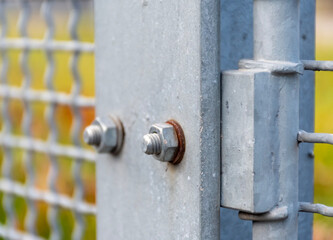Rusty bolts on a metal horizontal fence structure as an industrial technical textured detail