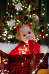 Little girl sitting in a gift box at Christmas day