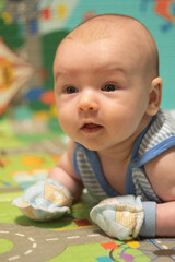 Newborn Baby lying on stomach in scratch mittens. Protect hands from accidental scratches. Babycare and safety