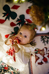 Little girl lying in Christmas pillows eating candy