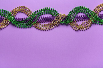 Colorful beads for Mardi Gras celebration on purple background