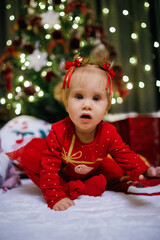 Little girl sitting near Christmas tree at the holiday