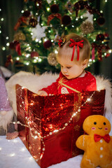 Little girl sitting in a gift box at Christmas day