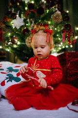 Little girl sitting near Christmas tree at the holiday