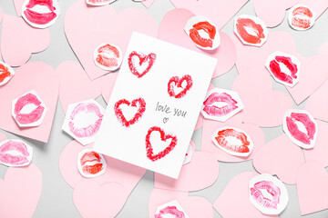Composition with greeting card, pink paper hearts and lipstick kiss marks on grey background....