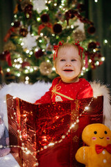 Little girl sitting in a gift box at Christmas day